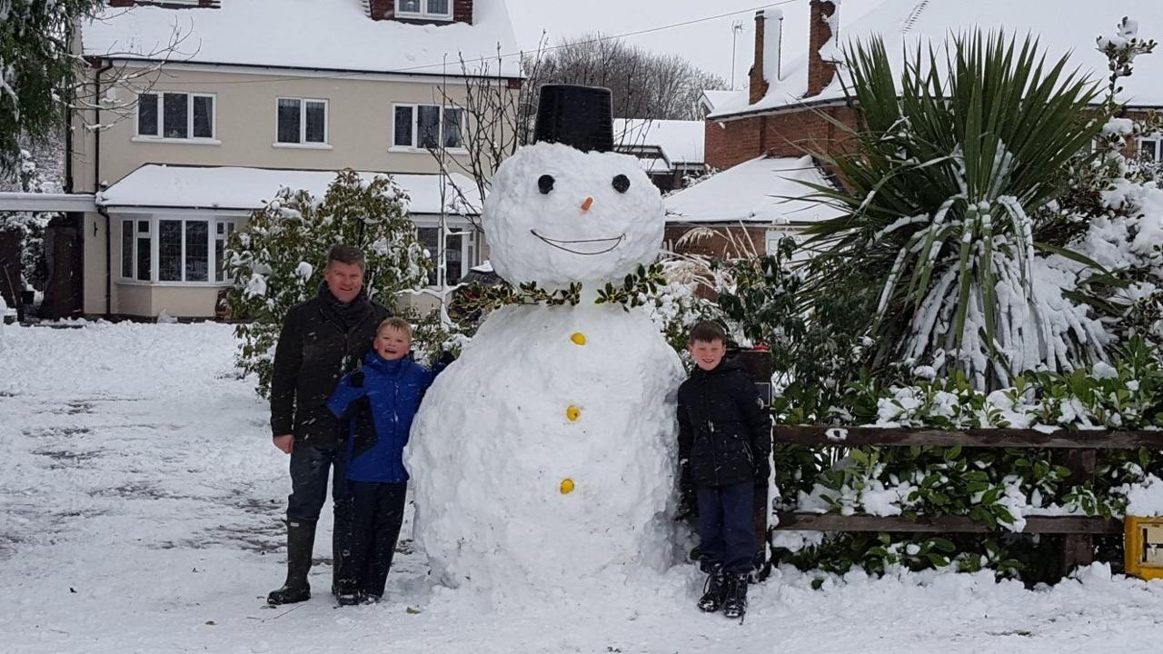 Family in the snow with a giant snowman