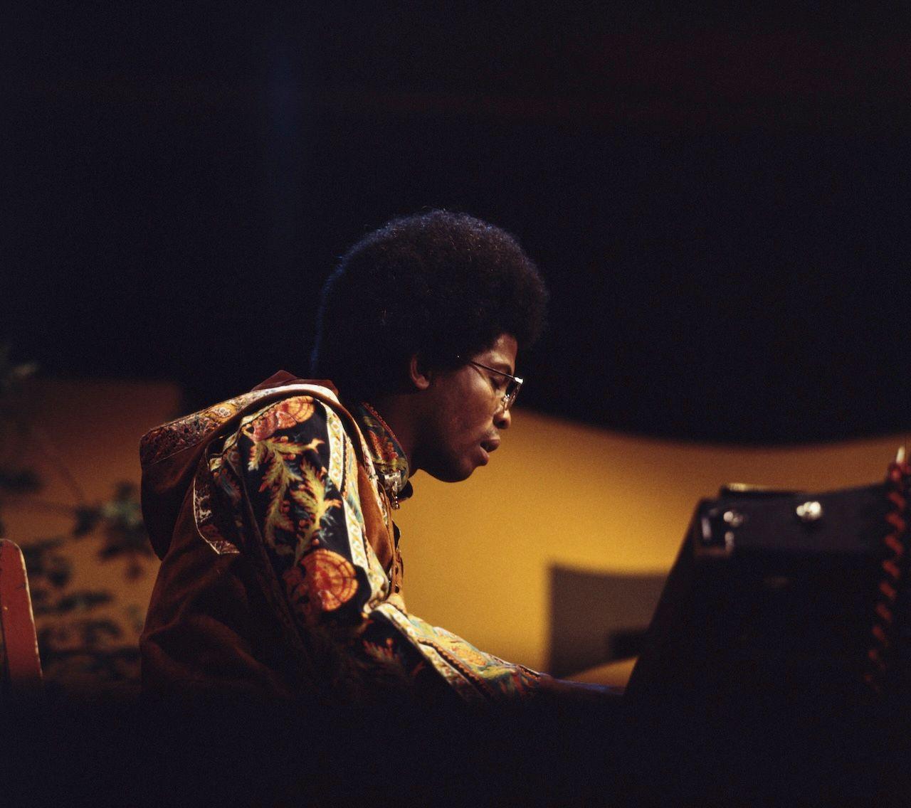 Herbie Hancock sat at the piano, wearing glasses and a psychedelic jacket