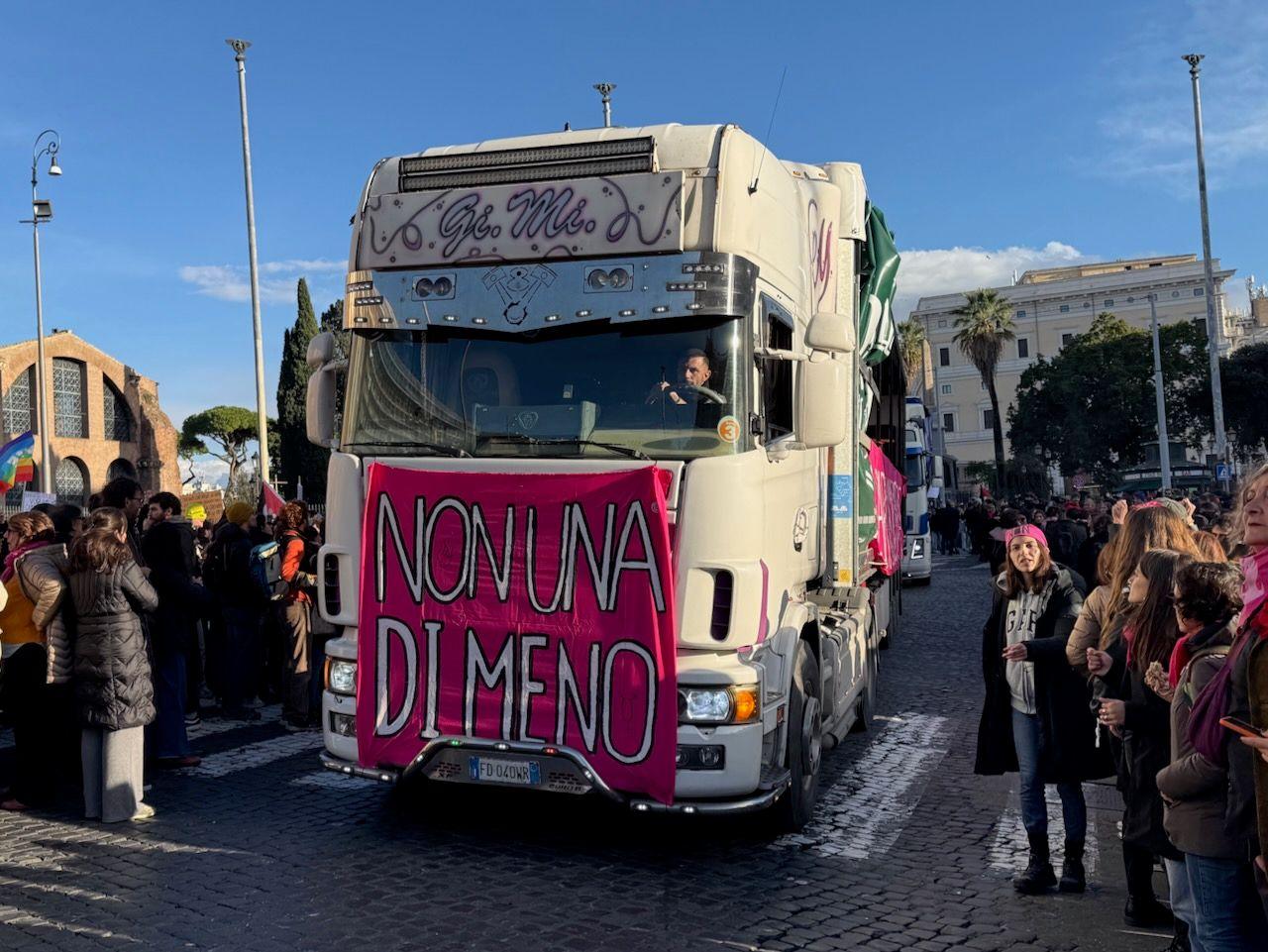 A lorry surrounded by crowds of largely women displaying a banner which says Non Una Di Meno (Not One Less).