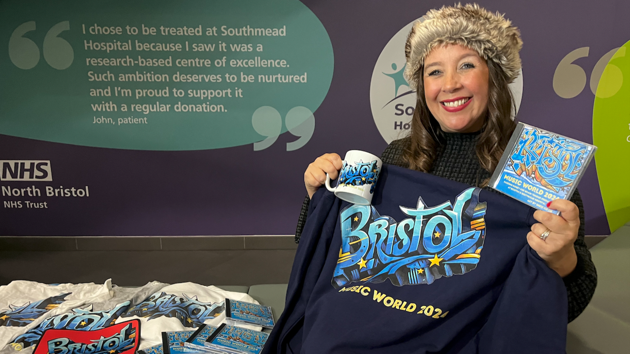 Harriet Annabell, singer, holding up products including a mug, CD and hoodie made for her Bristol Music World launch.