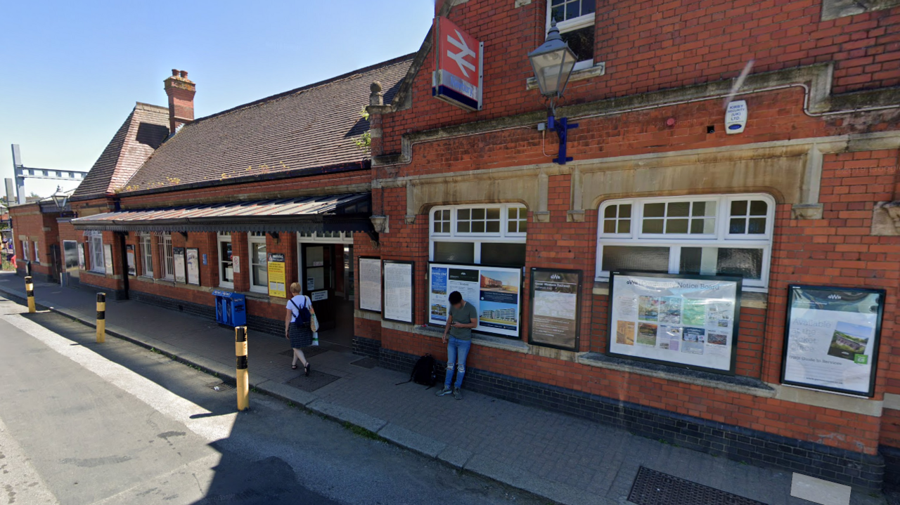 Google maps image of the front of Newbury station. It's a red brick building with a red train sign in the middle of the building. 