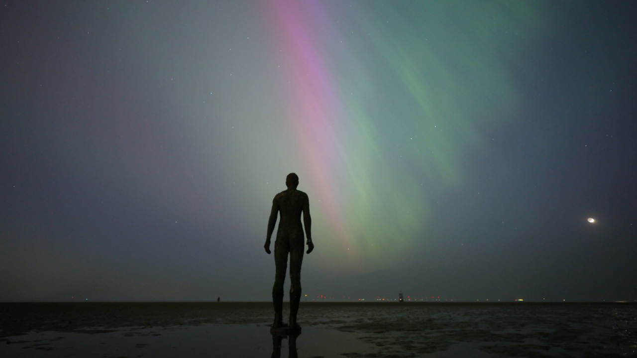 One of the statues silhouetted against a view of the norther lights