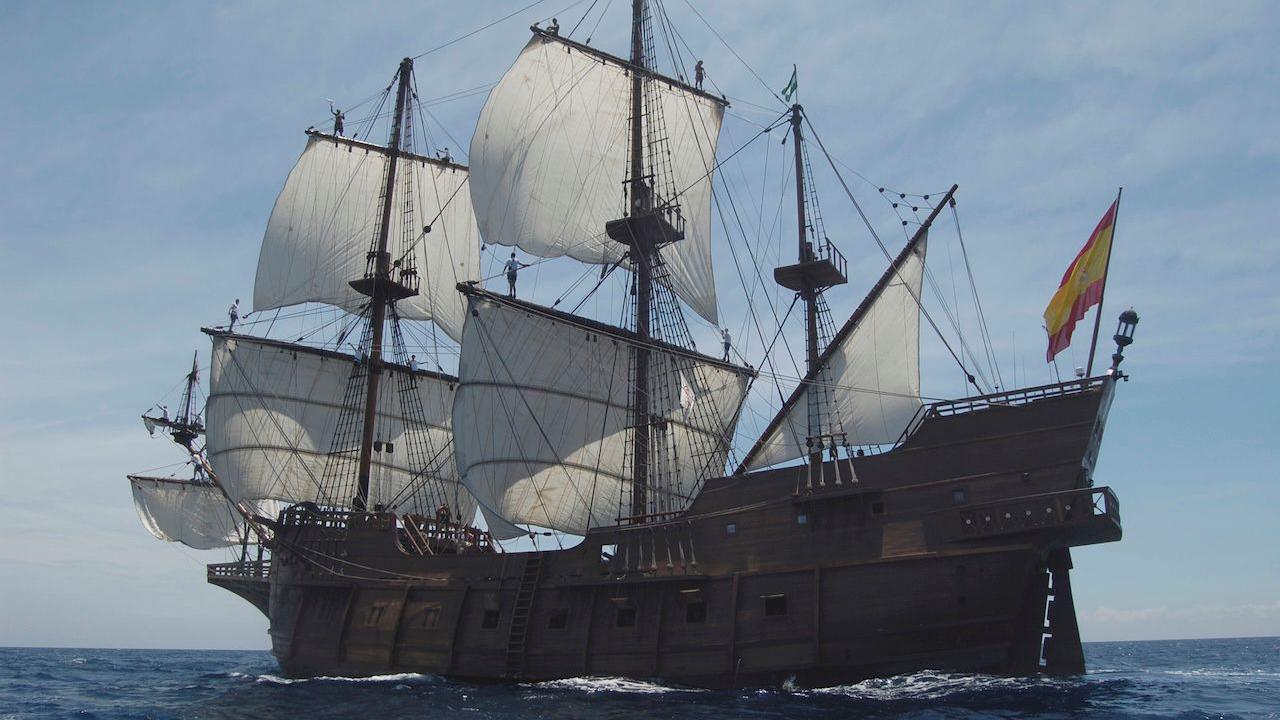 Galéon Andalucía with its large, white sails up sailing out at sea.
