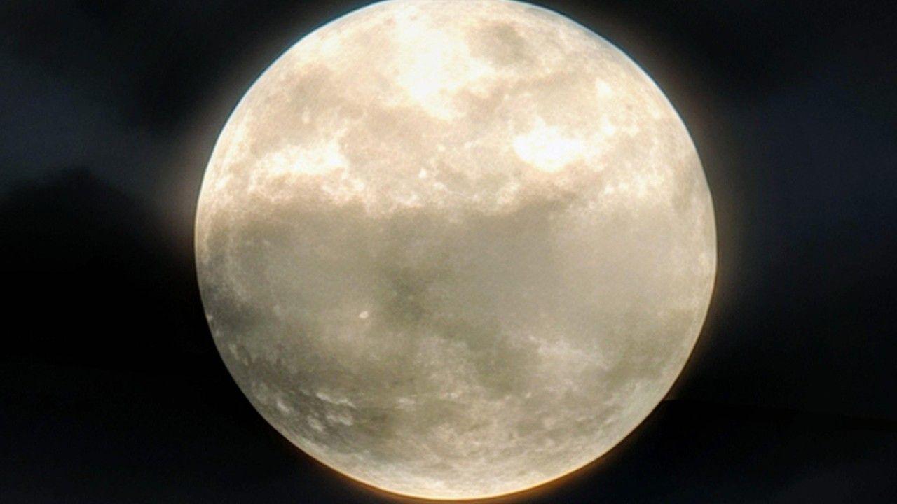 A bright silvery, white Moon shines brightly showing up some of the different areas on its surface