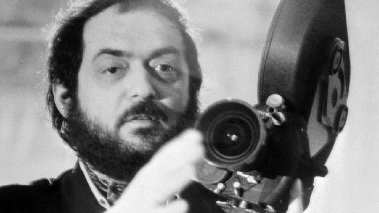 a black and white image of Stanley Kubrick holding a film camera,