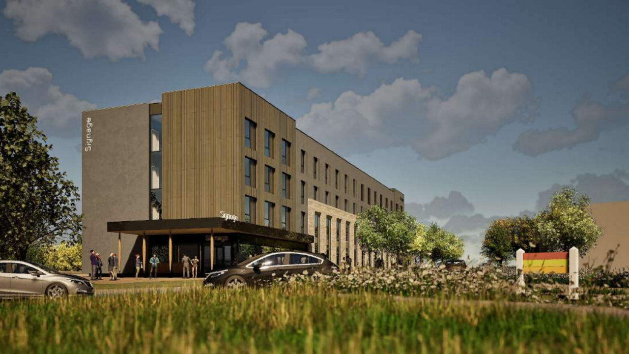 A computer generated image of a proposed hotel, with a grassy meadow close to the camera, and the grey and blocky building in the background. The signage on the hotel says 'Signage'