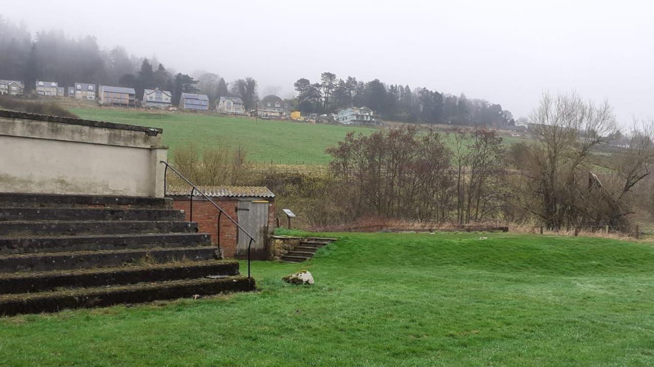 An old grandstand with a row of houses on the hill behind