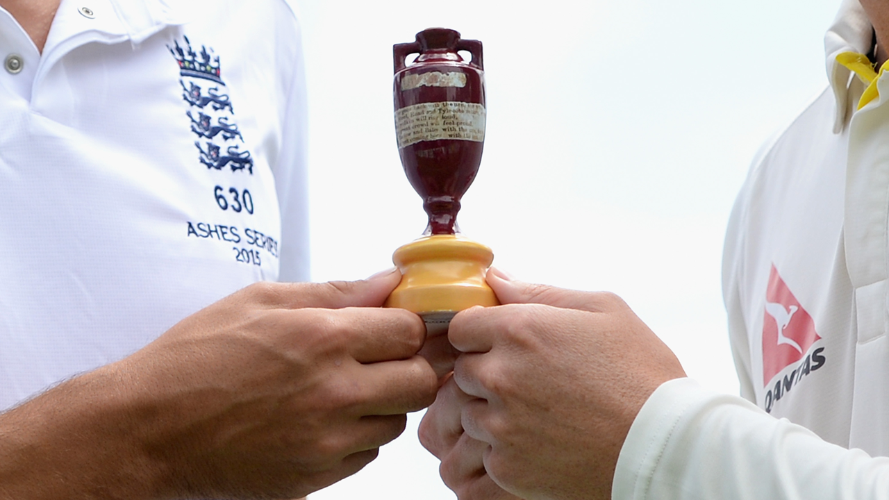 An England and Australia player holding the Ashes urn between them
