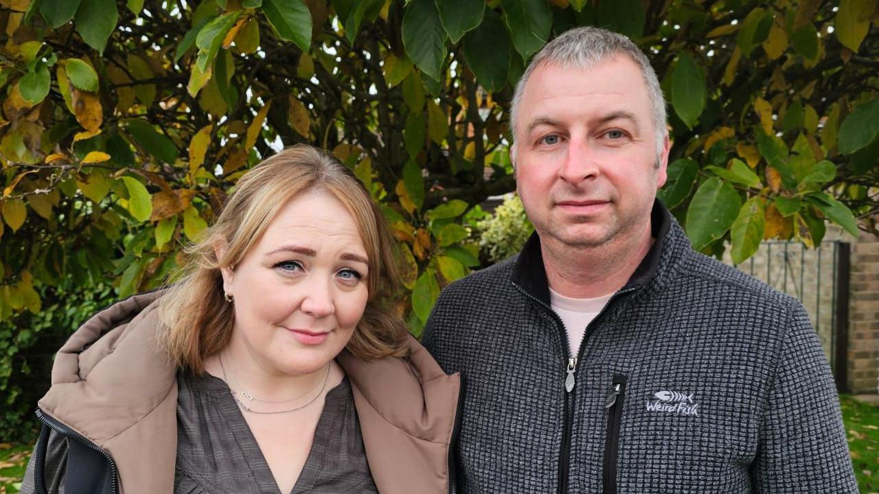 Rachel and Christian stand in front of a tree in their garden 