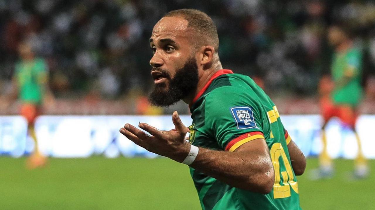 Bryan Mbeumo, wearing a green Cameroon shirt, shrugs during a football match