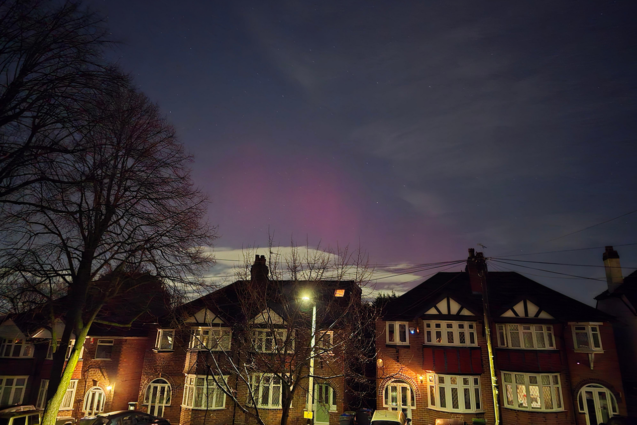 A row of semi-detached houses West Bromwich in the evening or early morning. A streetlight stands lit in front of the central house. Above them the sky is dark, but with a pinkish glow in the centre