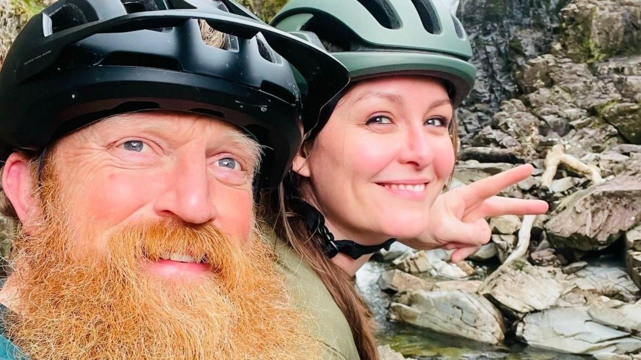 Close-up photo of Paul and partner Cheryl wearing bike helmets.