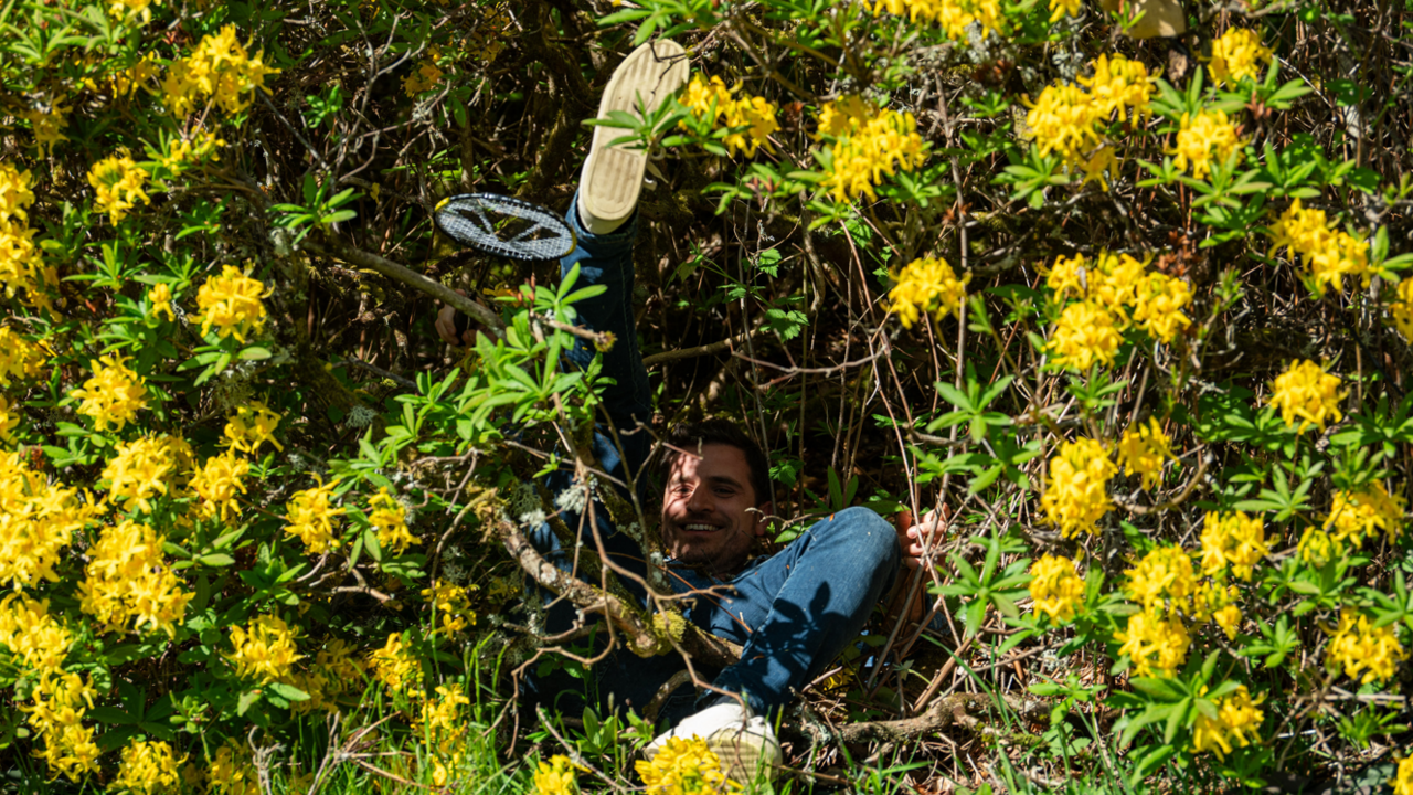 Alexander lying in a bush on The Traitors