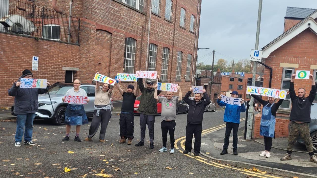People spread out across a road holding up handmade signs of support for Reece.