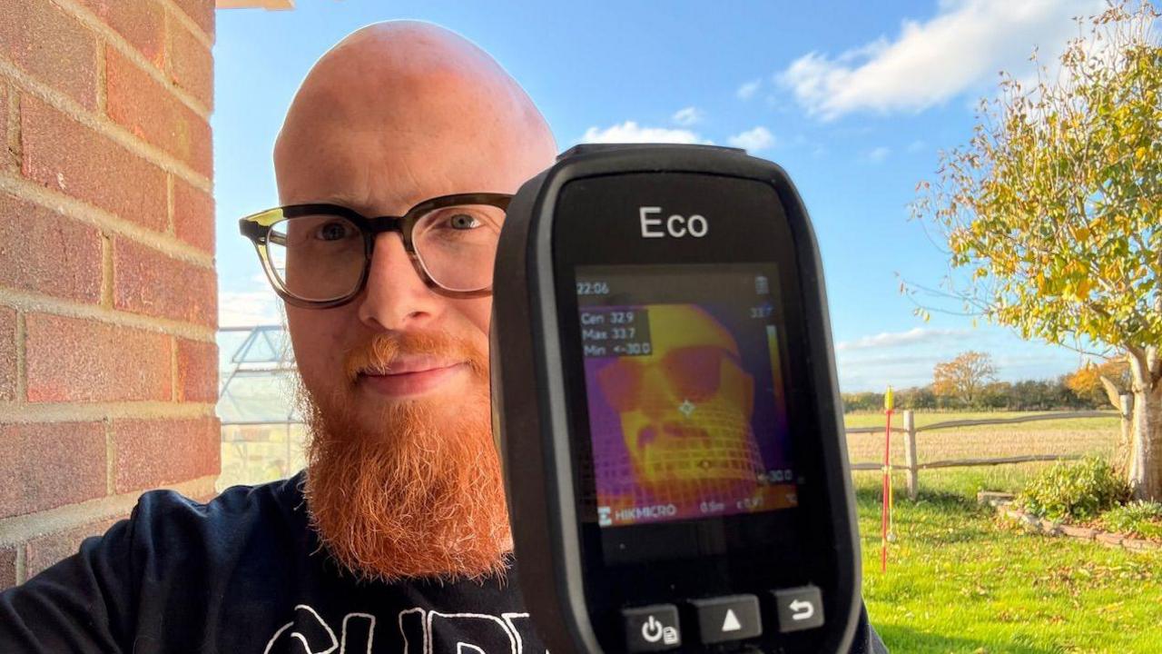  Jamie Matthews, with a big red beard, holds up a thermal imaging device