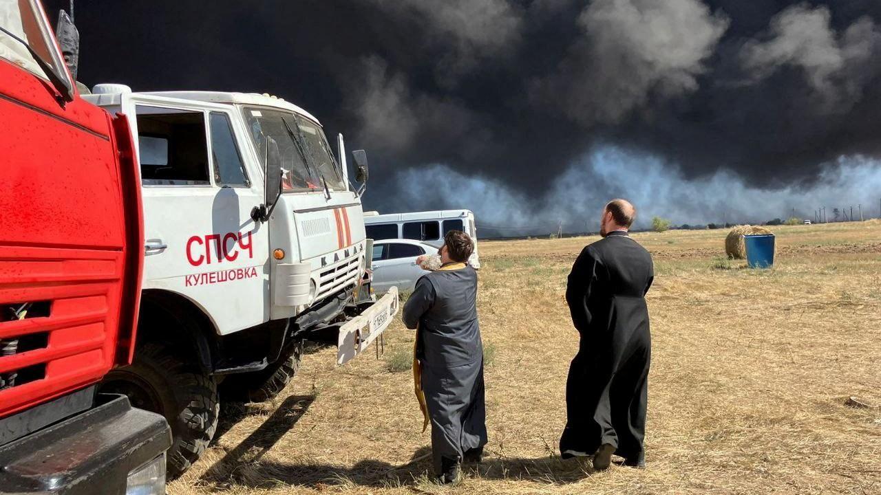 Russian Orthodox clergymen sprinkle holy water on fire trucks during a service near the scene of a fire at the Proletarsk fuel depot