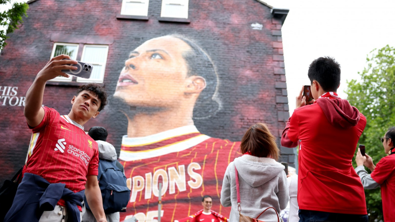 Fans take selfies next to a mural of the club's captain Virgil Van Dijk