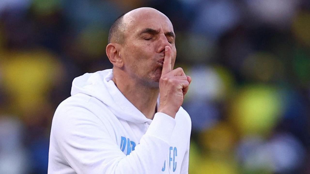 Krunoslav Jurcic closes his eyes and holds his right index finger to his lips