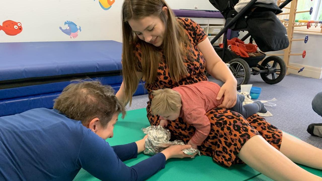 Oakley playing with his mother and a charity worker