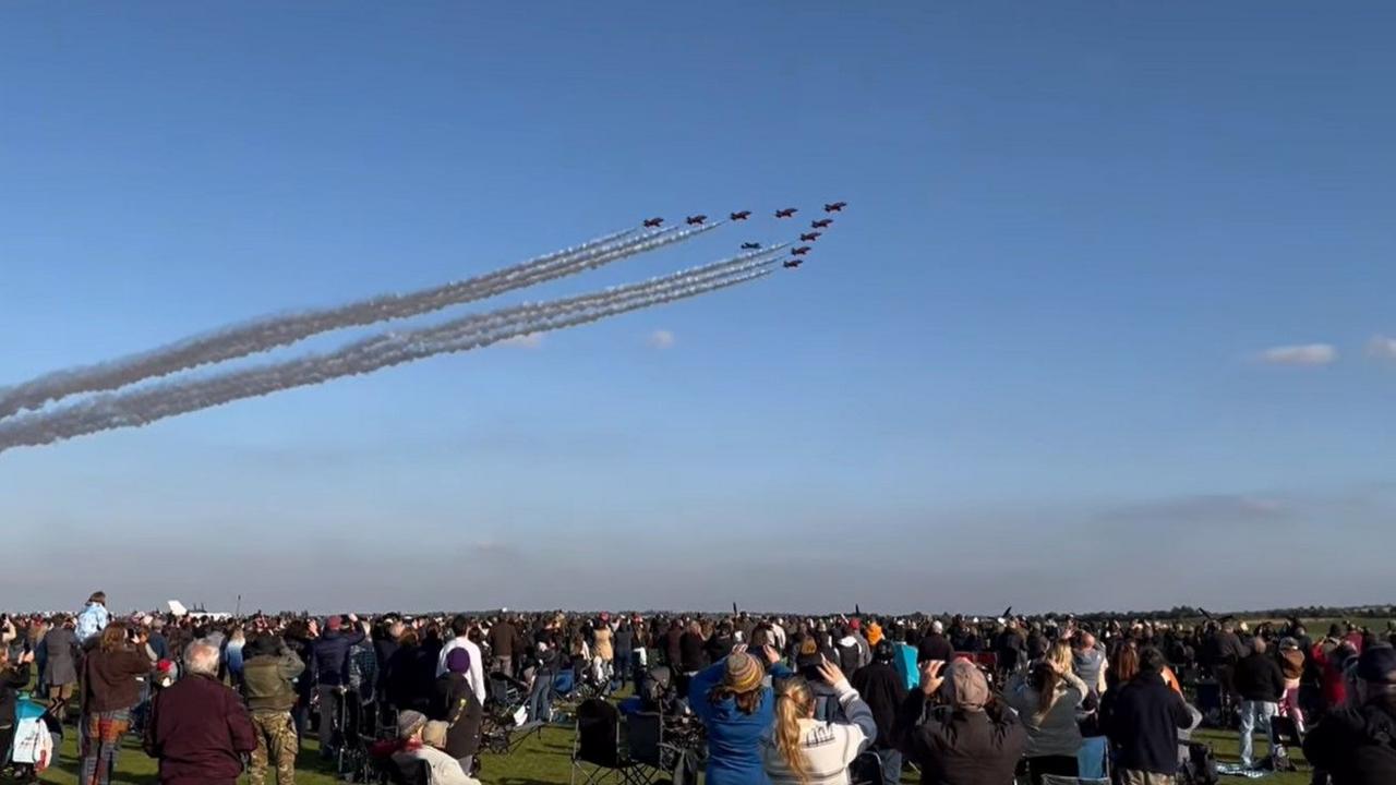 The Red Arrows display team is joined by a Spitfire as they fly in formation is a sunny day with clear blue skies.