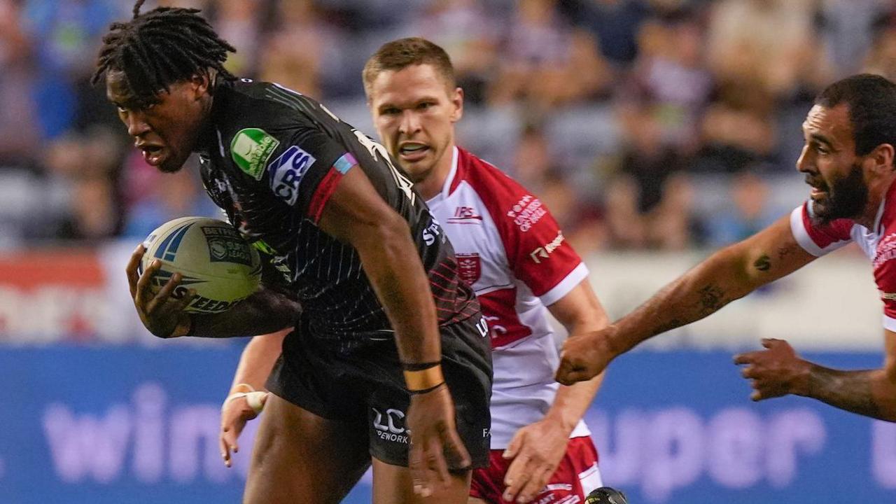 Junior Nsemba powers into space with the ball tucked under his arm for Wigan, as Hull KR's Tyrone May and Matt Parcell try to halt his progress