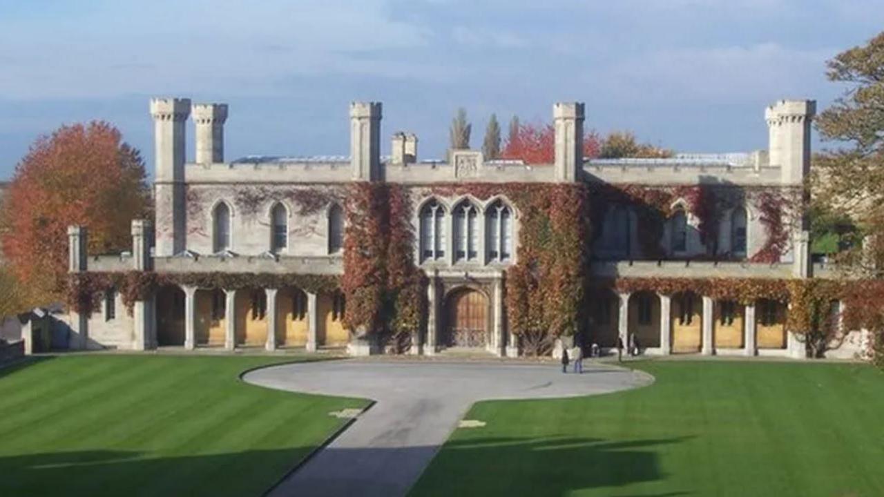 A front view of the grey-coloured historic court building in the castle grounds - with an area of lawn and a path in the foreground