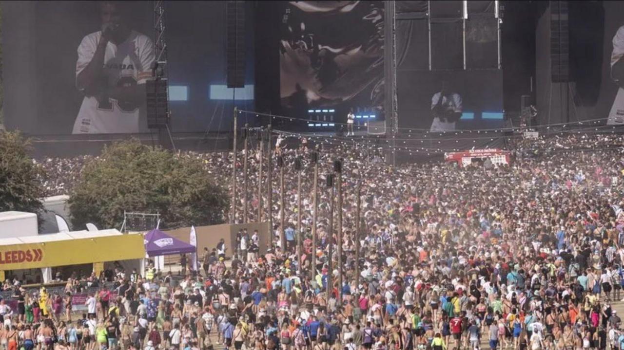 A crowd in front of the stage. A yellow banner on the left reads "Leeds".