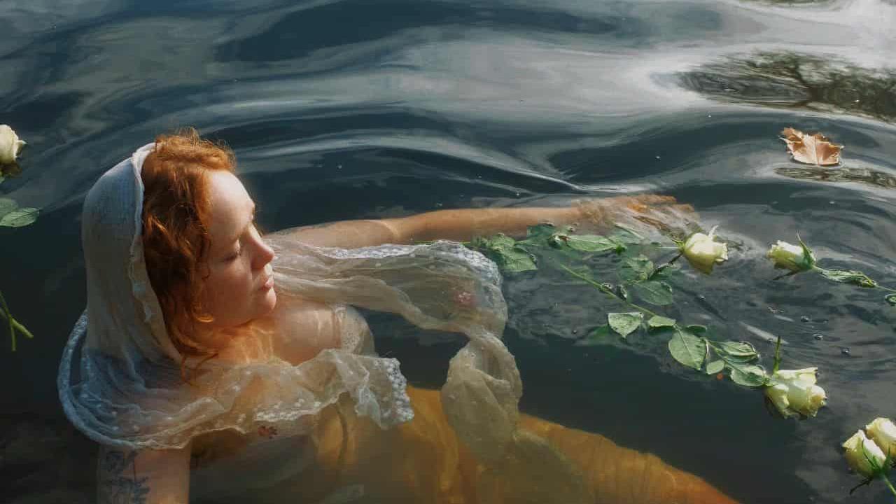 Meg is floating in the Avon with roses on the water.