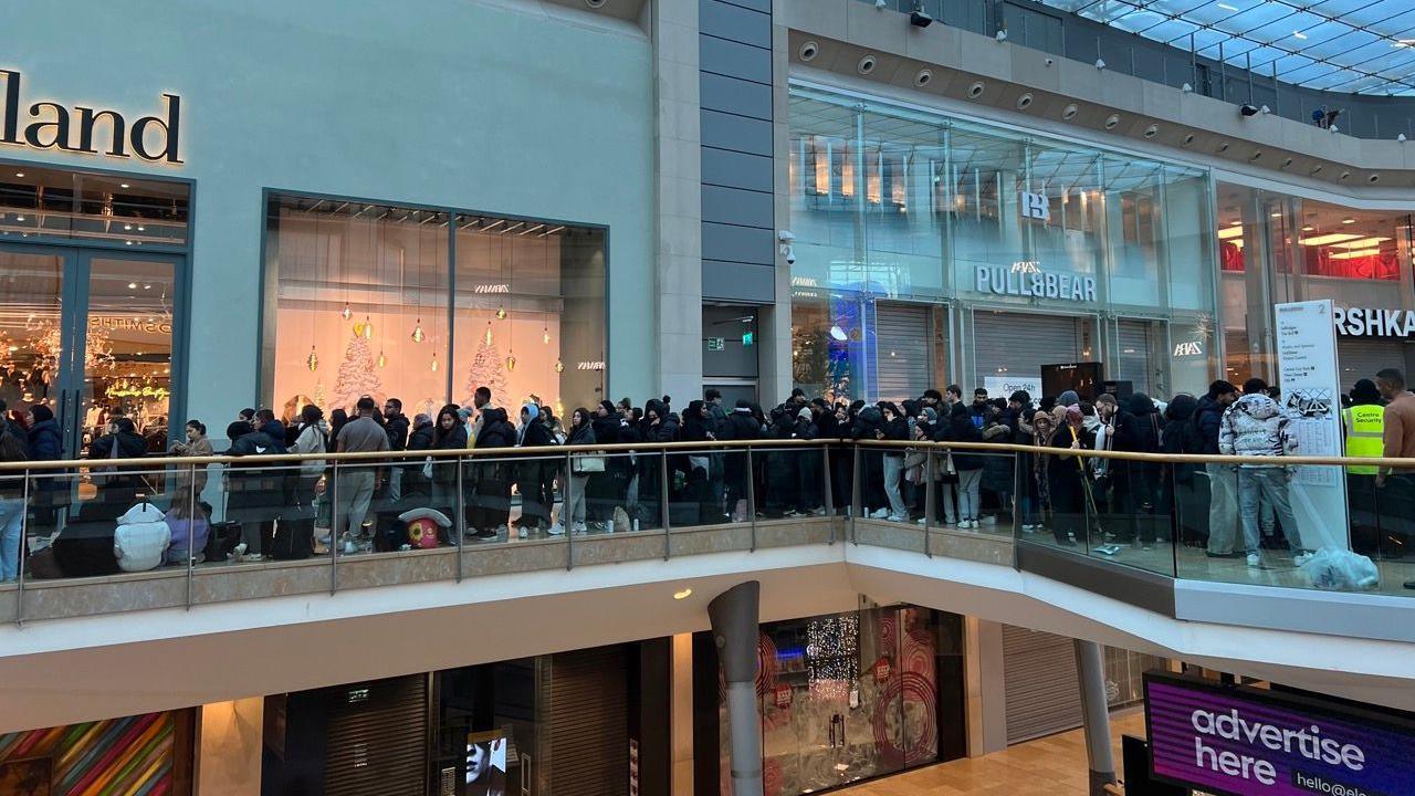 Crowds of people filling the top floor of the Bullring with shops in the background