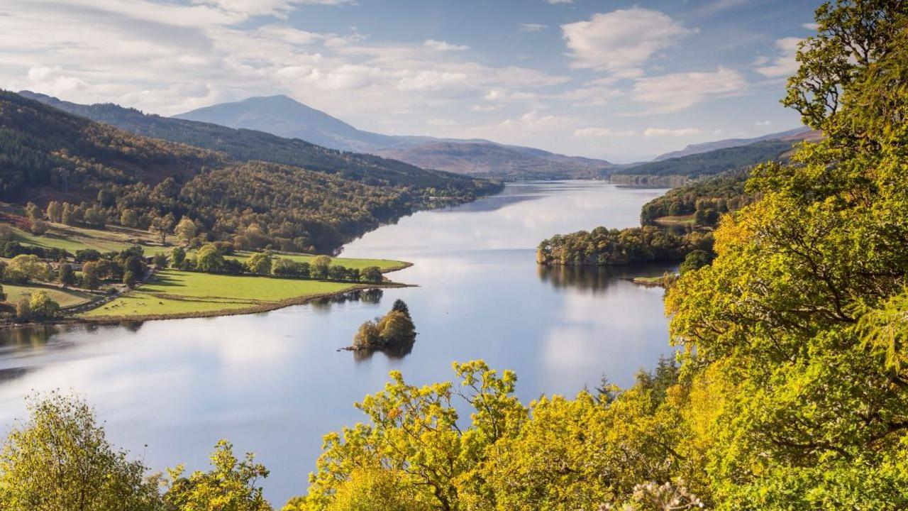 Loch Tummel surrounded by trees, with hills in the background