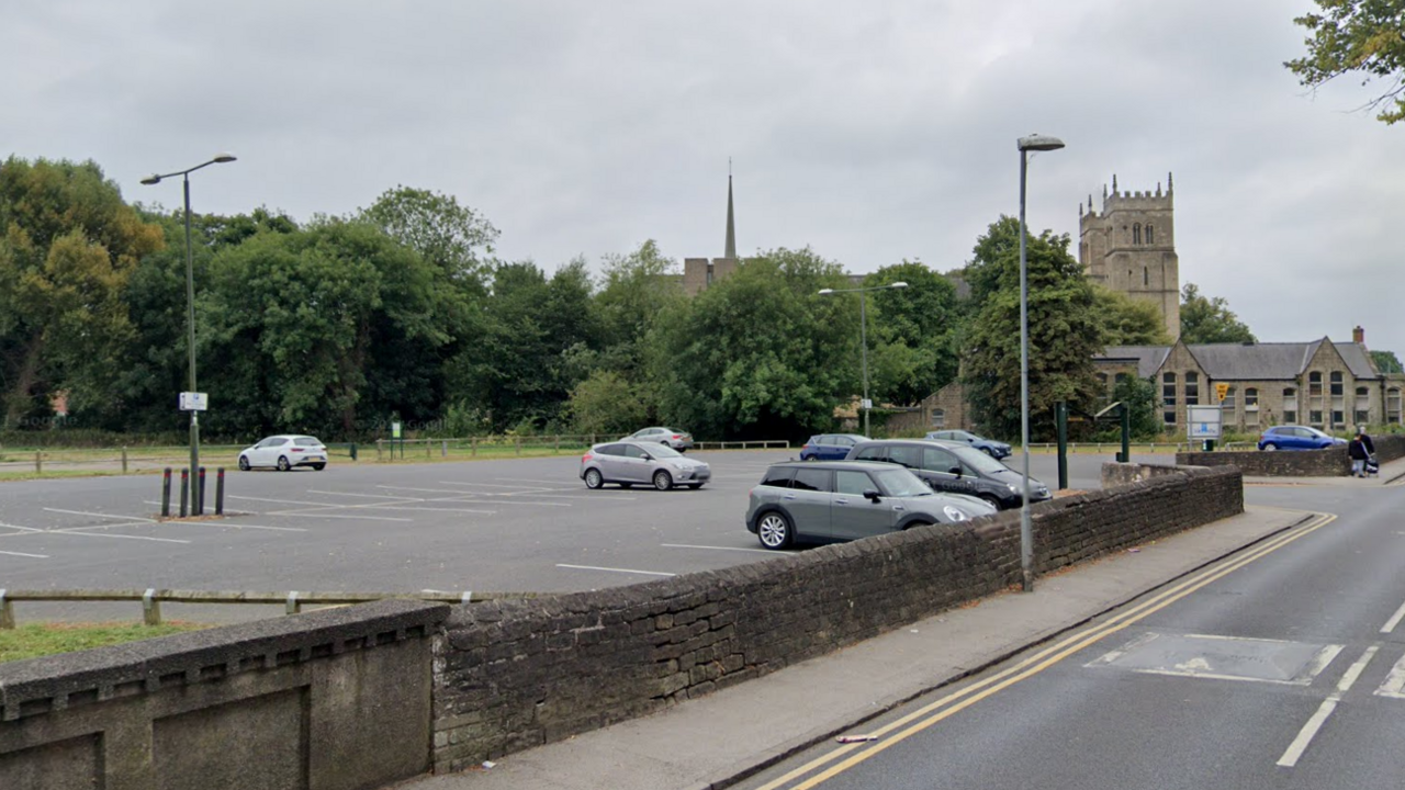 A car park with trees and church nearby