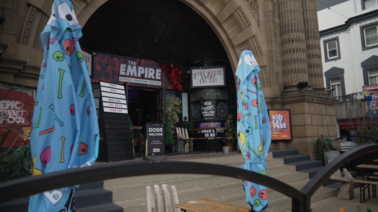 exterior of the doors of the Empire, showing promotional information and in the foreground, two closed blue parasol umbrellas