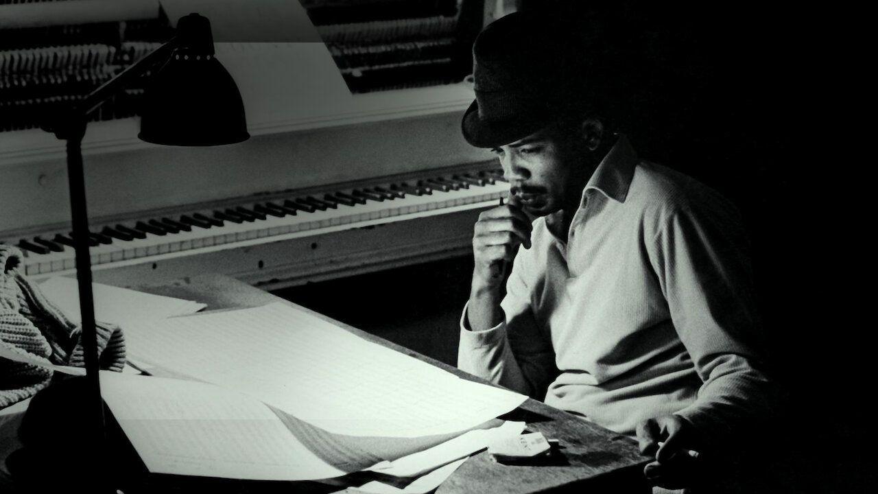 Quincy Jones in the recording studio, wearing a black hat and polo shirt