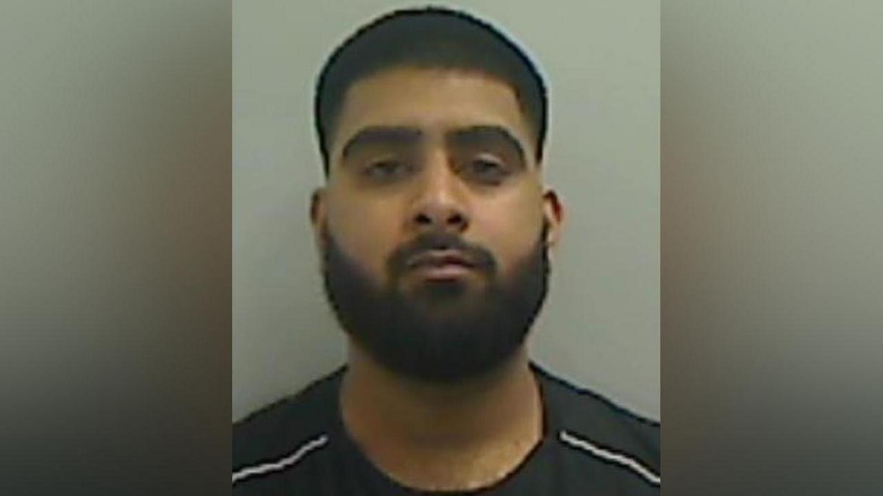 Mugshot of a man with dark hair and a beard