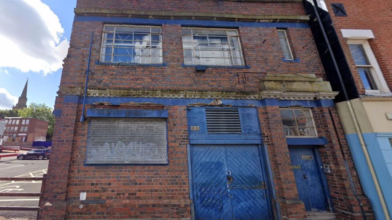 A street view image of 23 Temple Street. The red-brick building has a blue door and multiple windows