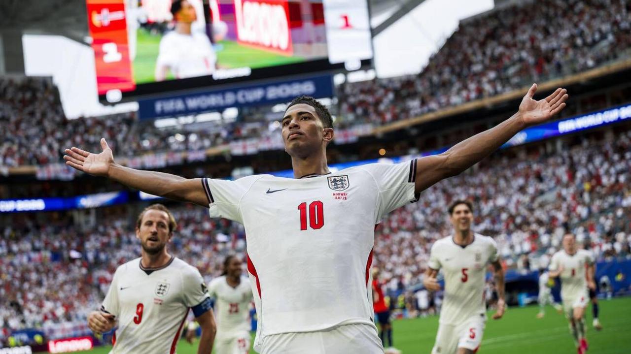 Jude Bellingham permanece de pie con los brazos extendidos y una expresión despreocupada tras marcar un gol para Inglaterra contra Noruega.