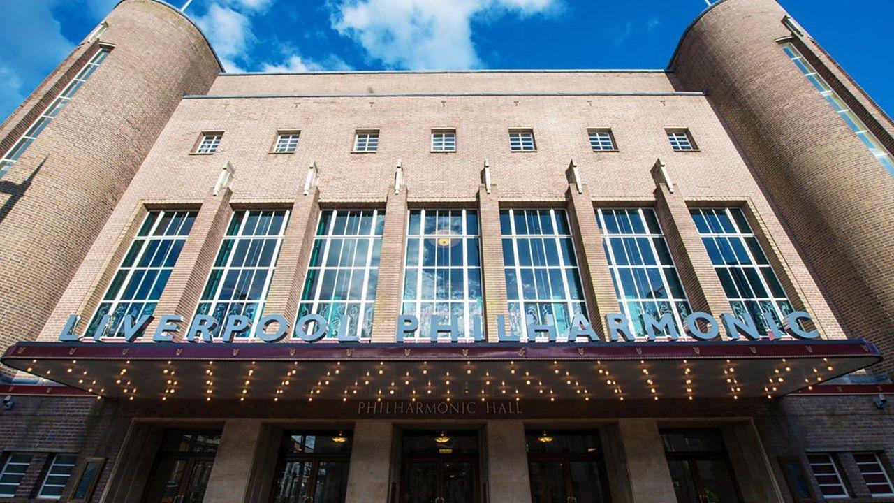 Fawn brick building with engraved glass of 3-storey height with receding tiers of parapets. Symmetrical front: between semi-circular stair turrets and a canopied entrance are 7 large vertical metal windows separated by piers topped by jagged abstract motifs.