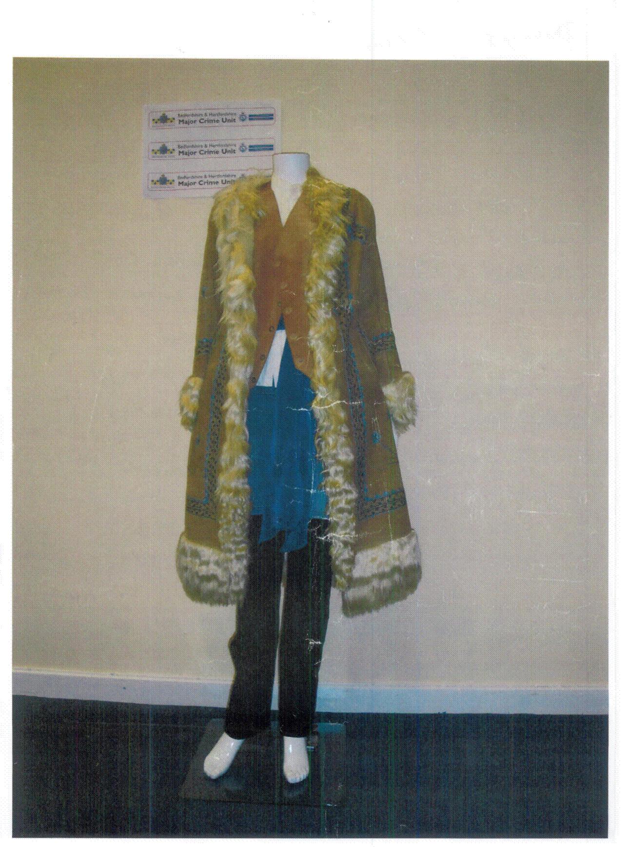 A mannequin wearing a brown Afghan coat, brown leather waistcoat, white cotton blouse, white cotton smock with a floral pattern and imitation lace, black jeans and a chiffon lace scarf.