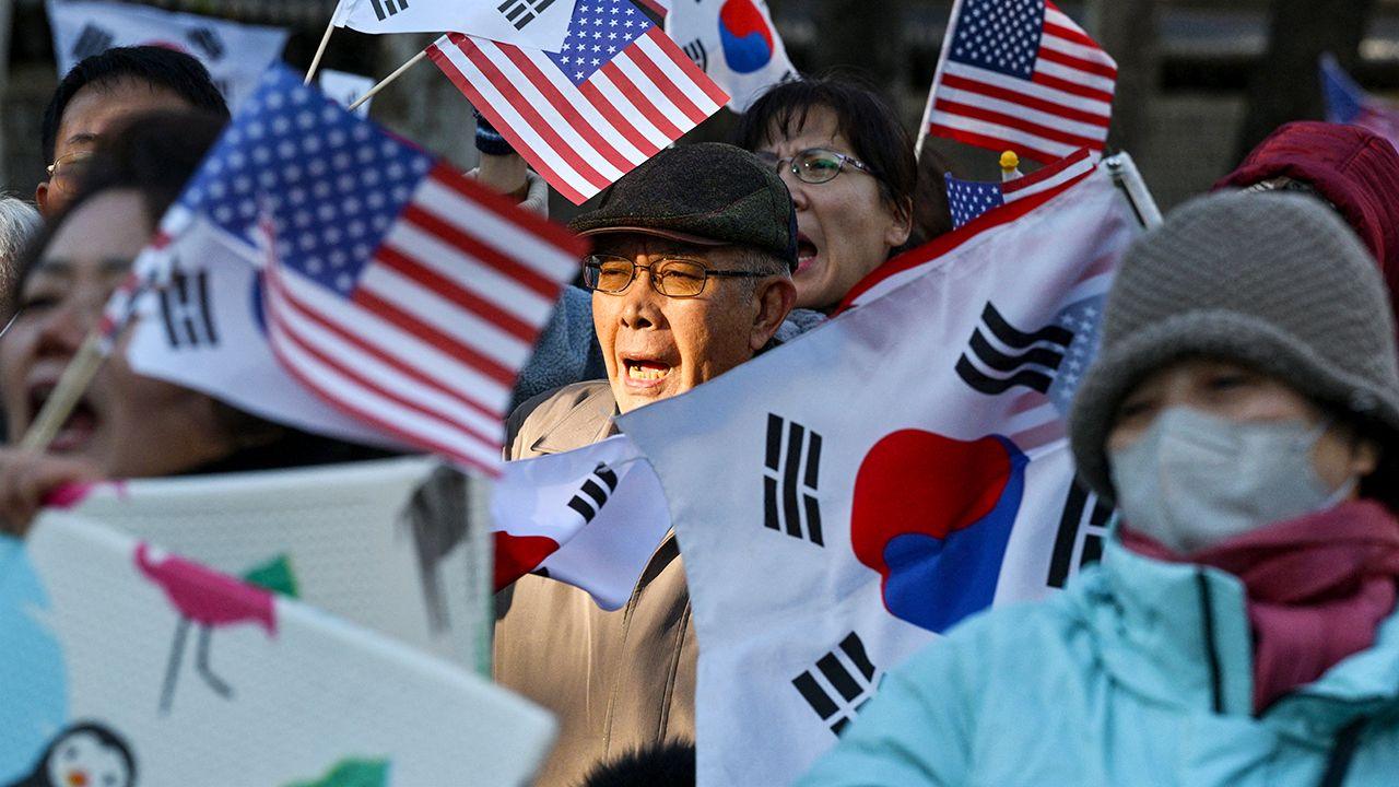 A group of men and women waving South Korean and US flags gather in Seoul to show support to the president on Wednesday