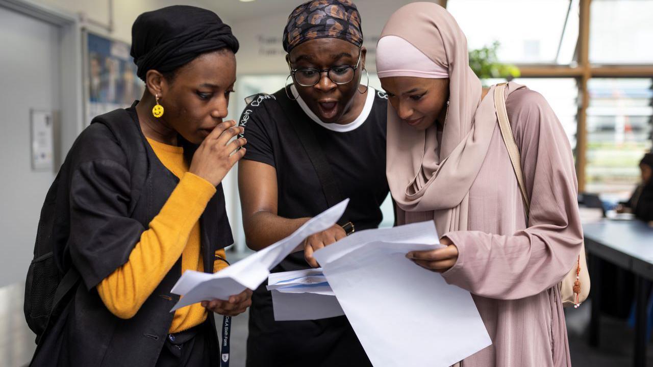 Three students look at their A-level results in shock. 
