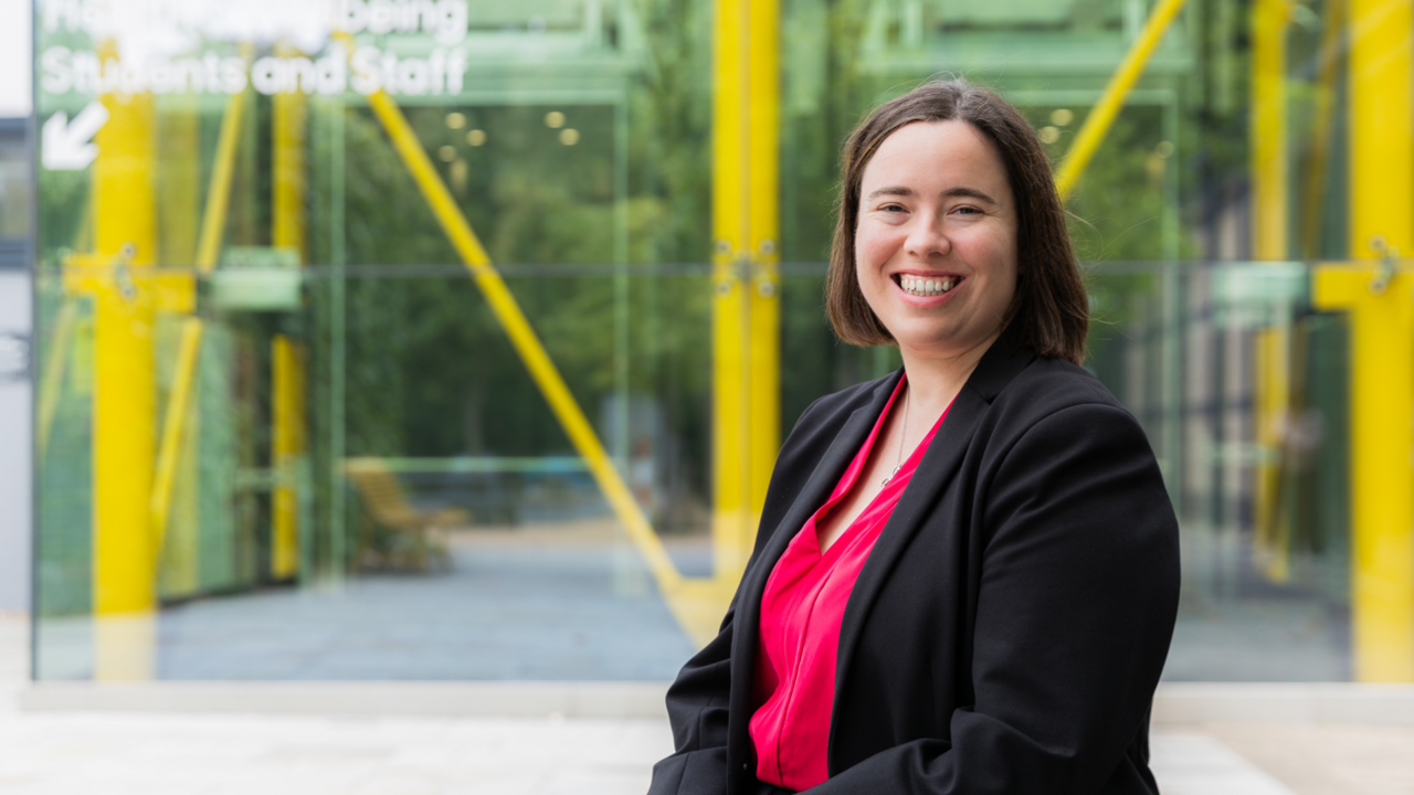 Dr Georgina Marsh, Head of Pharmacy at the University of Suffolk. She is smiling and wearing a black blazer over a bright red top.