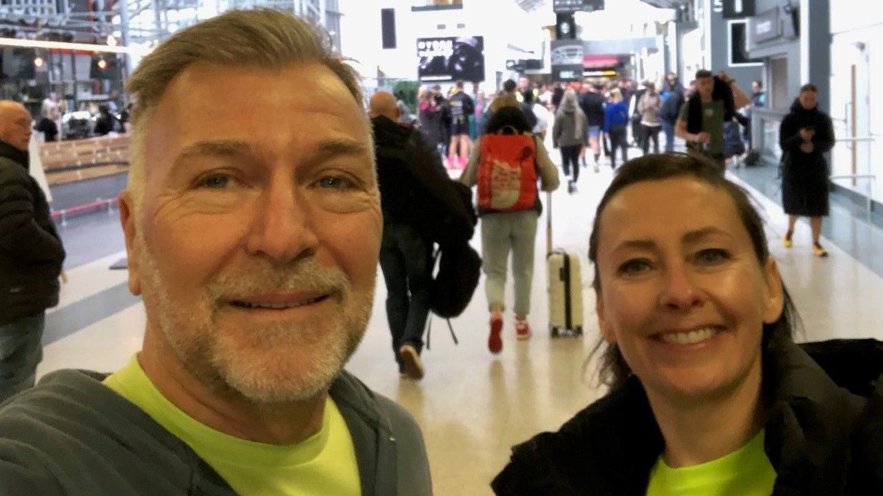 Keith Trotter and Vicki Simpson smile at the camera. They are both wearing bright yellow tops with jackets on top.