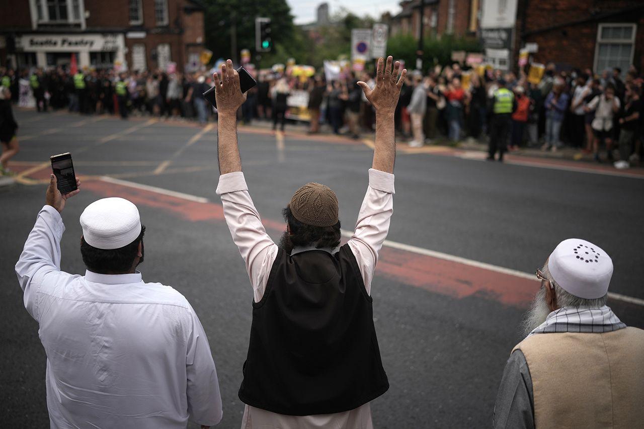 Three Muslum men gesture towards a crowd of anti-racism protesters in Sheffield on 7 August