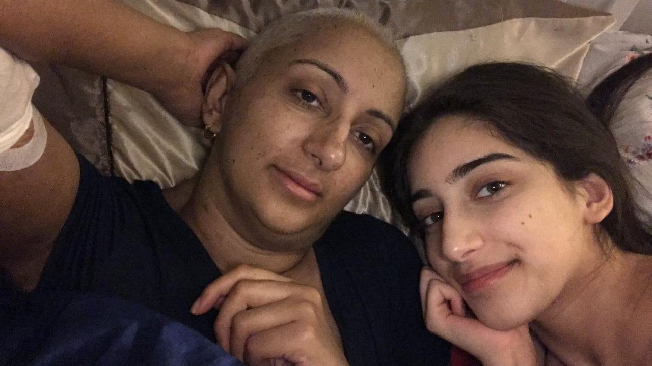 Kal recovering at home with her daughter. Two people look at the camera while lying down.