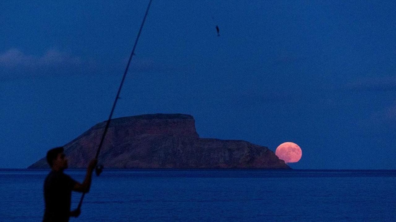 Fisherman in the Azores with the supermoon rising in the distance