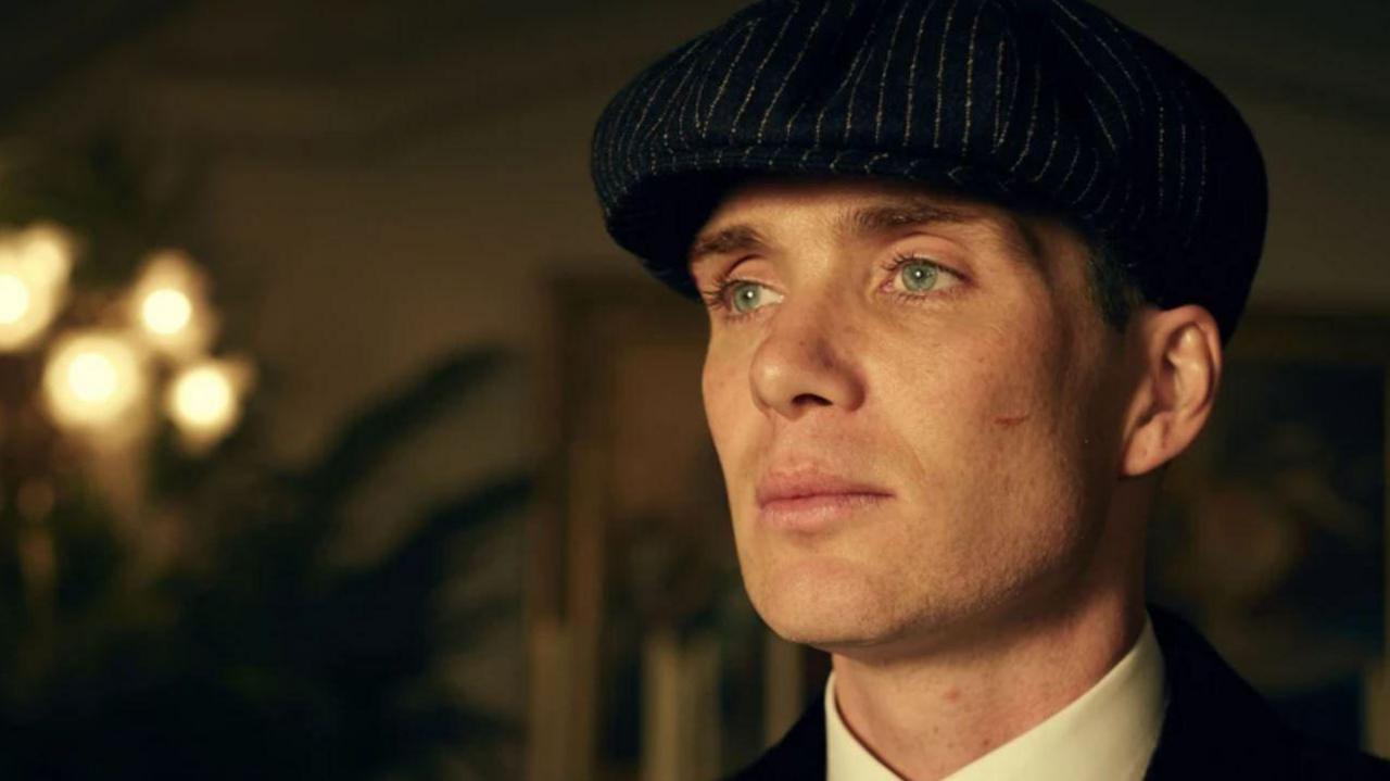 Cillian Murphy in character as Thomas Shelby wearing a cap and white shirt