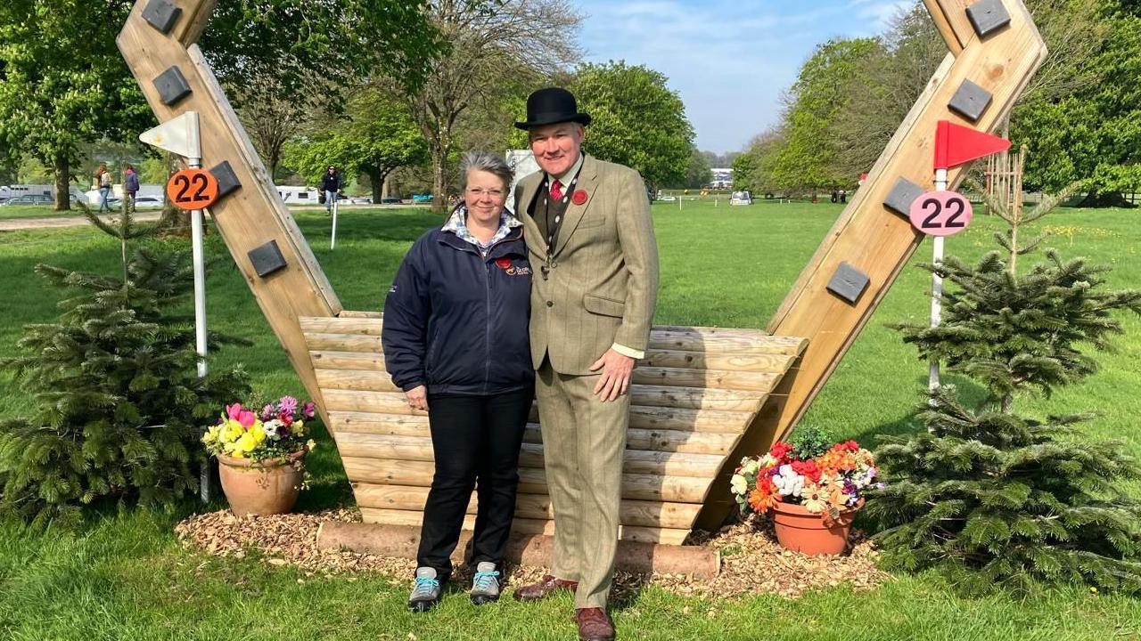 Emma and Martin have their arms around each other in front of a cross country jump.