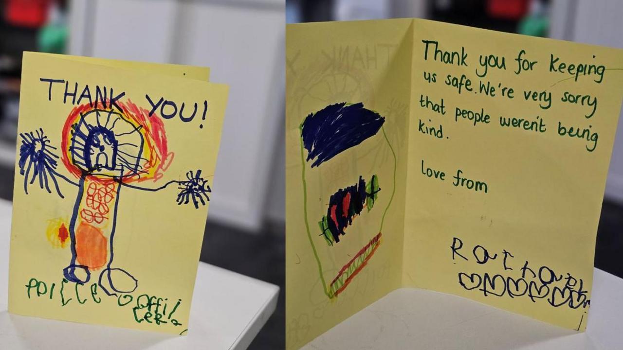 Two cards made on yellow paper by a young child with a child's picture of a police officer and the words "thank you" on one and the words "thank you for keeping us safe - we're sorry that people weren't being kind" on the other.