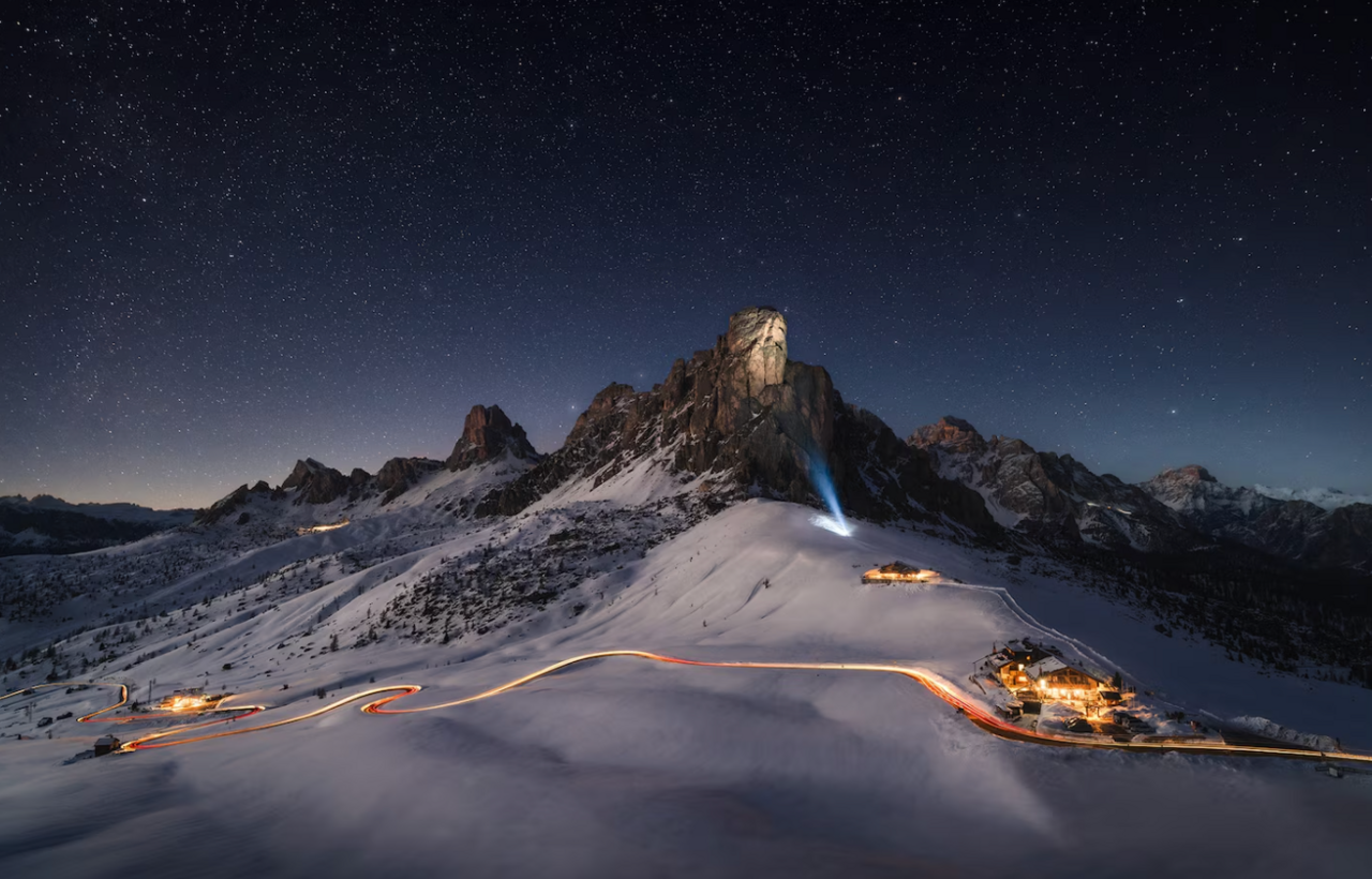 Snowy mountain scene lit up with cars passing