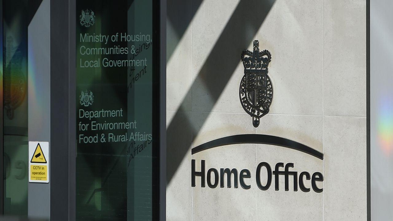 Entrance to the Home Office with signage on grey wall to the right and glass door to the left